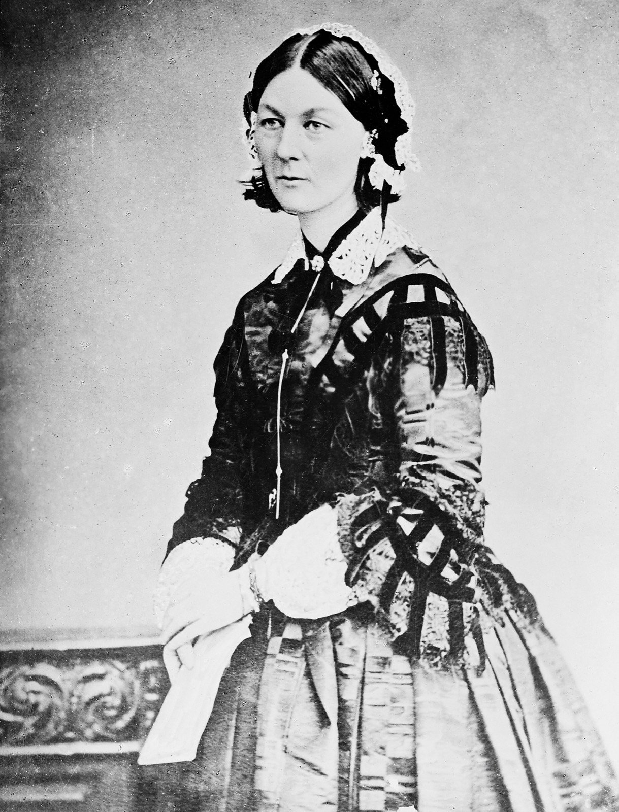 Florence Nightingale seated in a dark patterned dress in an 1856 photographic portrait