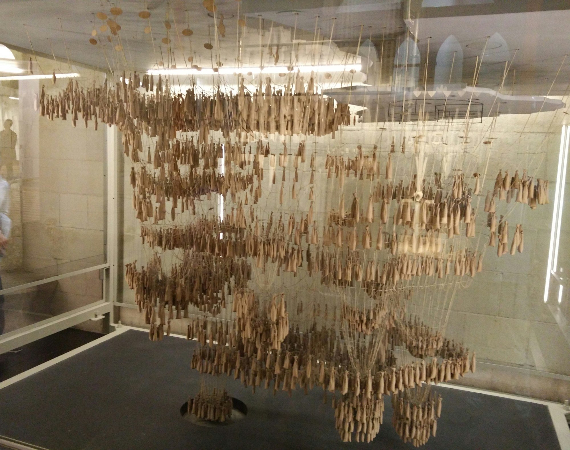 A hanging model of weighted strings suspended from a frame, forming the inverted shape of a church