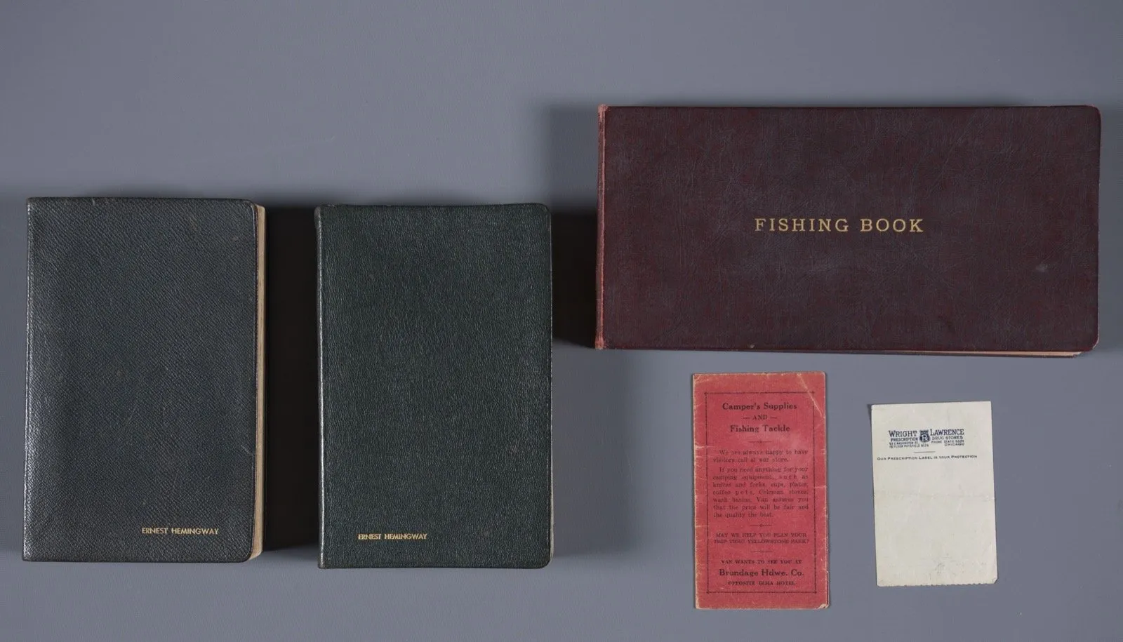 Hemingway's conserved logs on a table: two pocket notebooks stamped with his name and a maroon Fishing Book